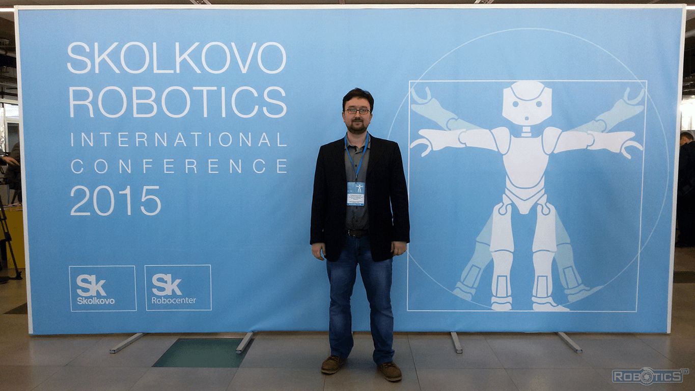 Vladislav Anatolevich Sychev near the conference logo.
